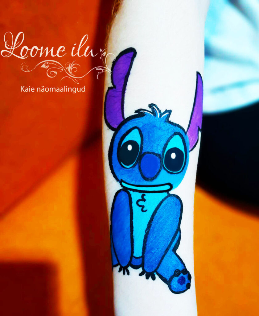 Stitch näomaaling, mis on käele joonistatud. Stitch on sinine multika tegelane, kellel on lillad kõrvad. 